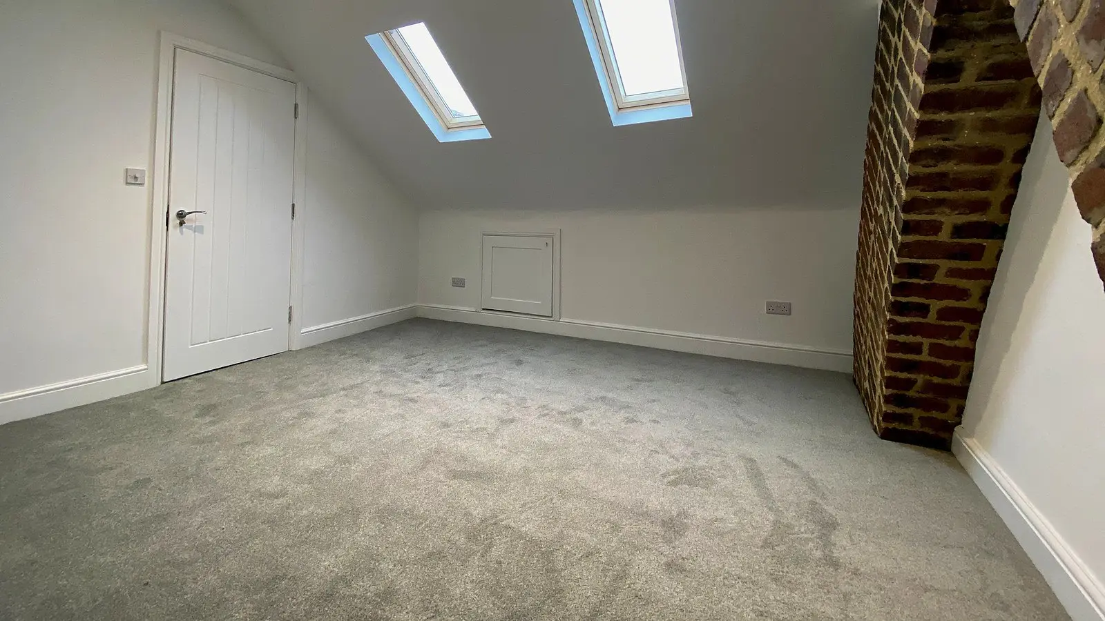 Finished loft conversion in a Bristol home with two roof windows and the original brick chimney breast left exposed