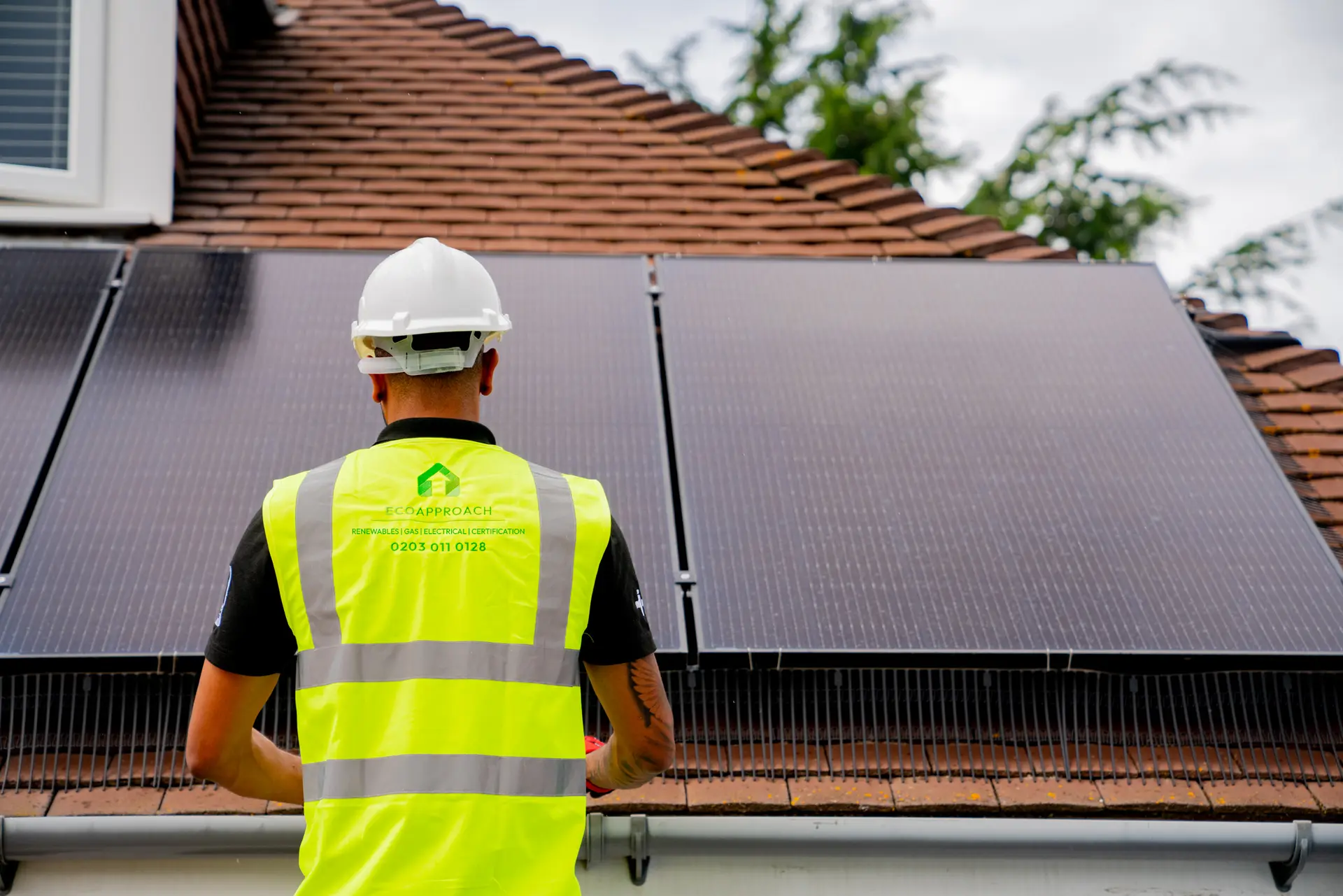 An installer on a roof beside solar panels