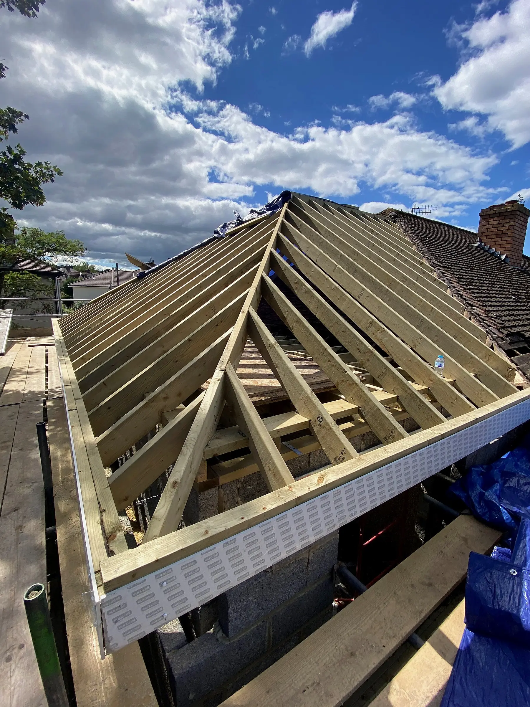 Hipped roof carcass against a blue sky