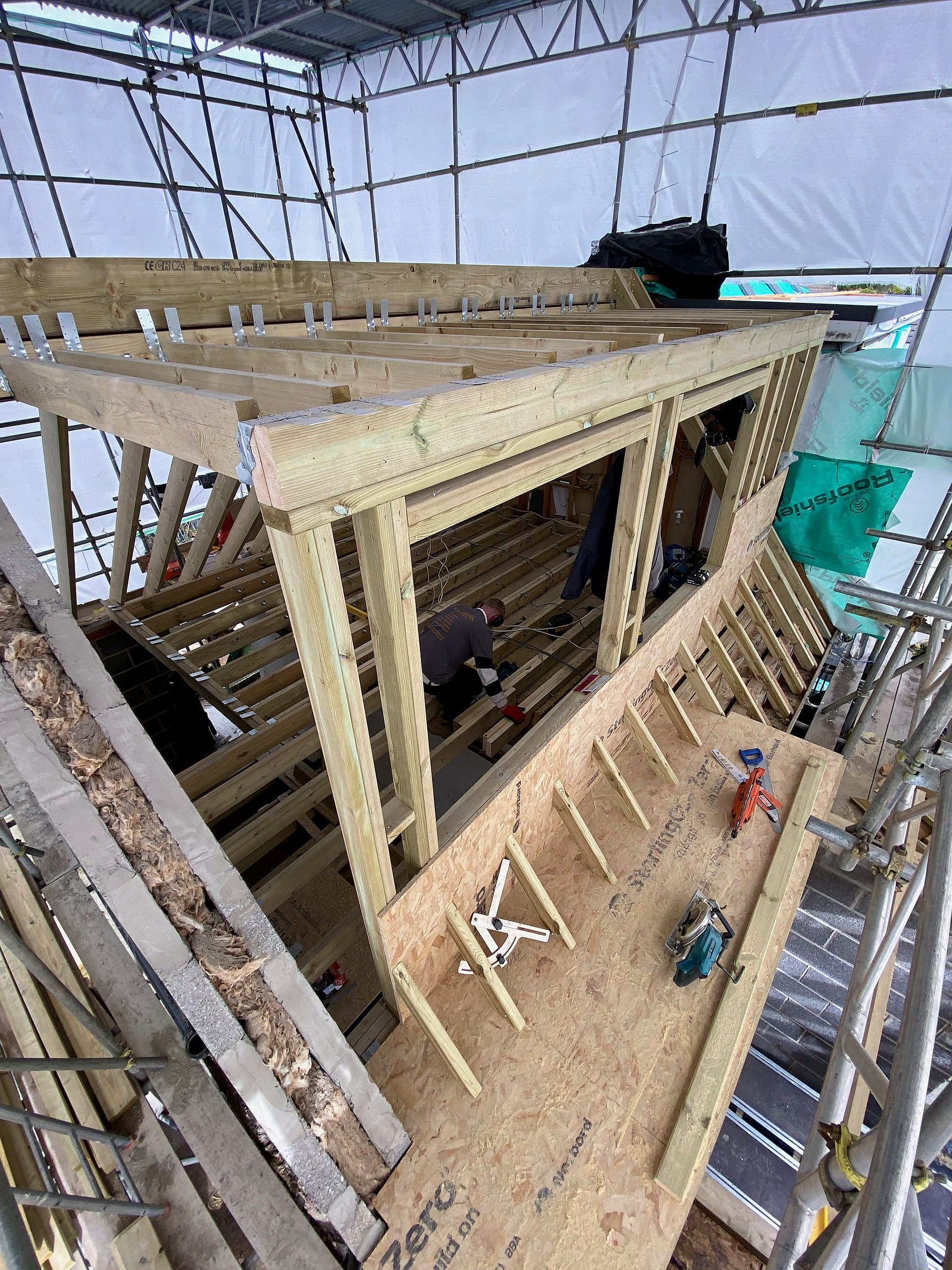 Dormer loft conversion frame under scaffold wrap on a Wilson & Cole site in Bristol